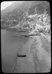 Skioptikonbild från institutionen för fotografi vid Kungliga Tekniska Högskolan. Motiv föreställande stadsbebyggelse vid bergssluttning nära strand, sannolikt i södra Italien. Bilden är troligen tagen av John Hertzberg under en resa i Europa..