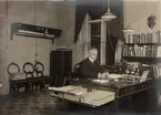 Fotografi ur album tillhörande Ester Holmberg, anställd vid Telegrafstyrelsens statistikavdelning 1902. Fotografierna troligen tagna 1907. Bch Hamilton vid skrivbordet.