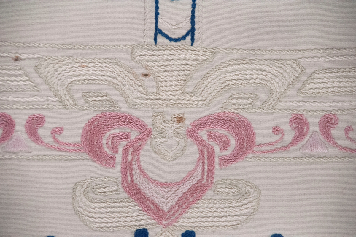 Bomullslerret, falda og brodert med attersting.