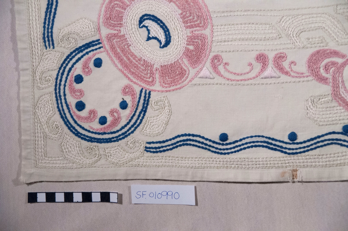 Bomullslerret, falda og brodert med attersting.