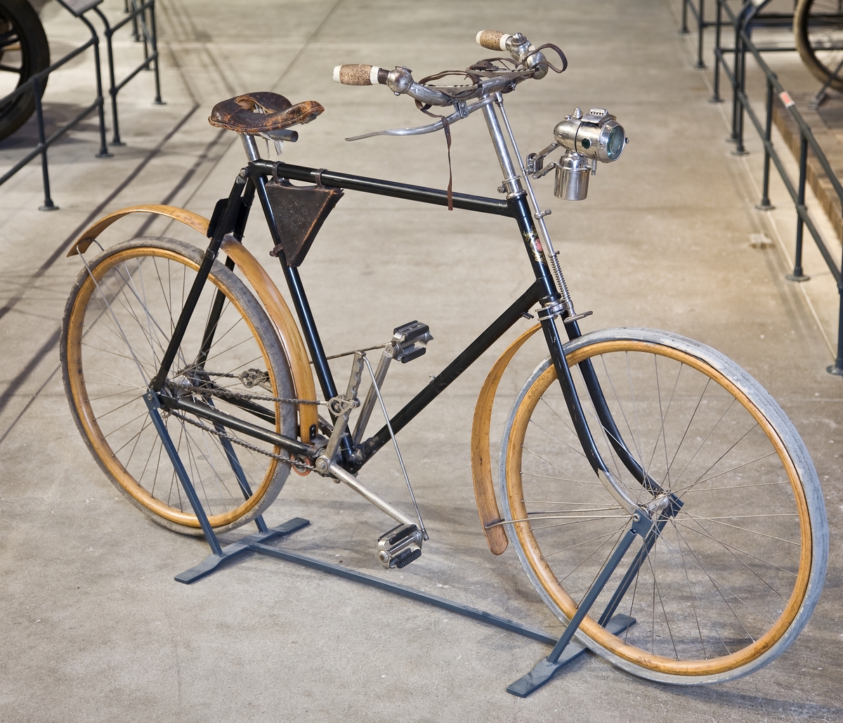 Herrcykel av typ upp-och-nertrampare (till skillnad från rundtrampare). Upp-och-nedgående pedaler med kedjor till baknavet som är en s.k. rullspärr enl. Birger Ljungströms konstruktion, patenterad 1892. Rullspärren ger frihjulsfunktion. De fram-och-återgående kedjorna ger baknavet en roterande rörelse genom två excentriska "drivskivor". Fem tryckluftsreglerade växlar. På styret finns två gummiblåsor dolda under metallhöjle. Luften leds med slangarna till ytterliggare två gummiblåsor placerade på segmenten vid tramporna. Broms på bakhjulet genom att de båda tramporna trycks ned och påverkar en hävarm som trycker två roterande koniska bromsklotsar mot bakdäcket. Senare modell hade s.k. skedbroms mot bakdäcket. Framhjulsbroms med s.k. skedbroms mot framdäcket. Fälgar och skärmar av trä.
Tillbehör: Verktygsväska, signalklocka, skylt med polisens ordningsnr, 6808.