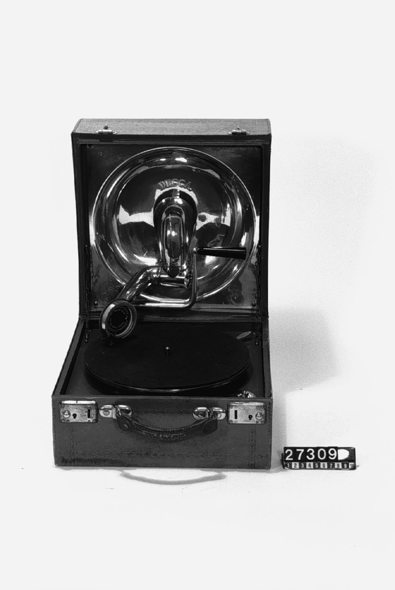 Resegrammofon, "Decca", med skålformad ljudtratt och ljudarm av aluminium på insidan av locket enligt engelskt patent år 1914. Med verk och dosa från Schweiz. Skylt i lådan: "Keith Prowse & Co Ltd. Branches all over London". Ljuddosan: "Dulcephone trade mark swiss made. For all gramophones. The New "Crescendo soundbox". Stämplat på ljudarmen: "Regd 631877 Patent 3033".