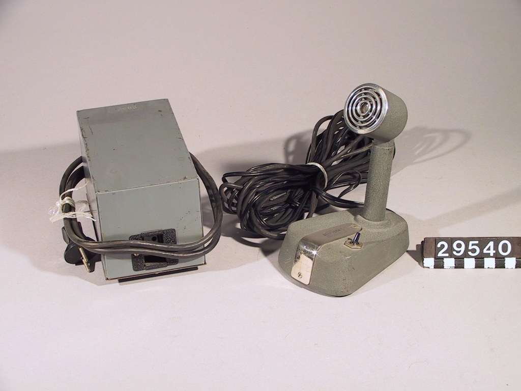 Trådspelare. Mikrofon och nättrafo separat. Förvaras i trälåda med bärhandtag. Tråddiktafonen är i 4 delar: 1 st. tråddiktafon, 1 st. bordsmikrofon (typ typ M 5040-2), 1 st. transformator och 1 st. trälåda. Tråddiktafonen har en 2 meter lång sladd för anslutning till transformatorn. Transformatorn har en 1 1/2 meter lång sladd för anslutning till elnätet. Bordsmikrofonen har en 4.8 meter lång sladd för anslutning till tråddiktafon. Lådans längd: 400 mm, bredd: 300 mm, höjd: 530 mm. Bordsmikrofonens längd: 140 mm, bredd: 95 mm, höjd: 190 mm. Tråddiktafonens längd: 340 mm, bredd: 195 mm, höjd: 290 mm. Transformatorns längd: 180 mm, bredd: 100 mm, höjd: 110 mm. Skylt: Bolinders tråd-diktafon M 4050-2.