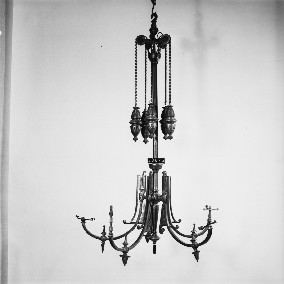 Takarmatur med fem brännare, avsedd för gas. Jugendstil, utförd i metallprofiler och gjutjärn. Blånerad, delvis gulmetallplätering. Passande lampkupor är L906-L912, numera TM40009-TM40015.