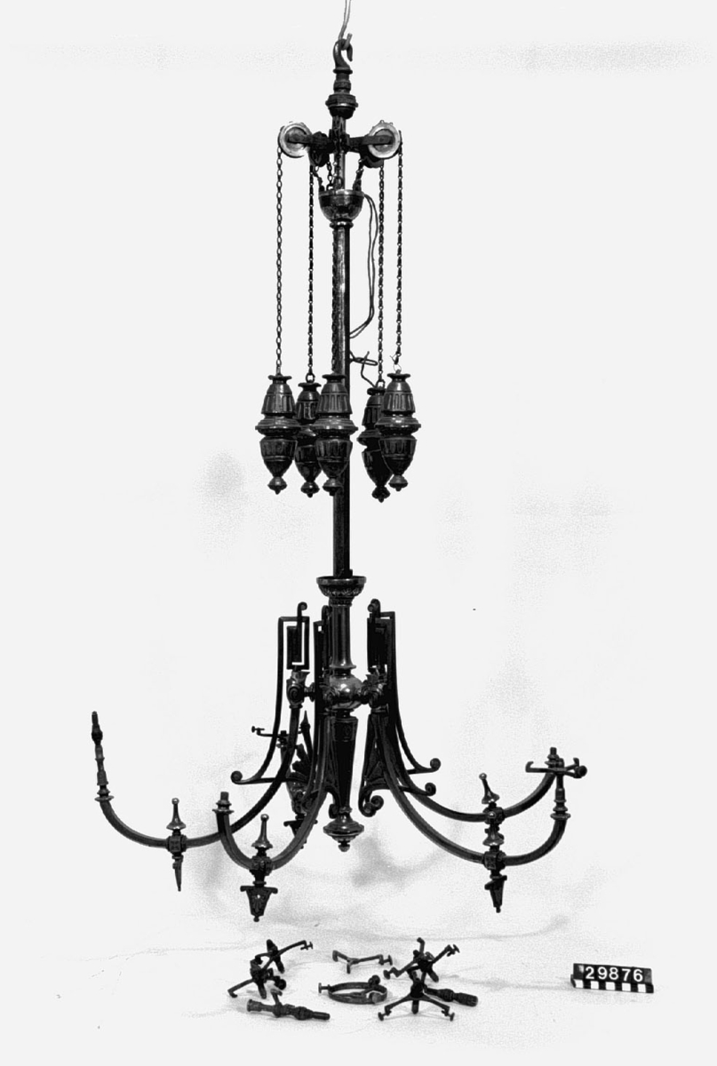 Takarmatur med fem brännare, avsedd för gas. Jugendstil, utförd i metallprofiler och gjutjärn. Blånerad, delvis gulmetallplätering. Passande lampkupor är L906-L912, numera TM40009-TM40015.