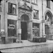 Skioptikonbild med motiv av port vid lampbutik i Lübeck.
Bilden har förvarats i kartong märkt: Resan 1907. Lübeck 8. 2