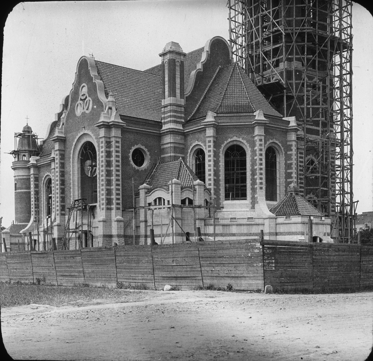 Skioptikonbild med motiv av uppförandet av St. Johannes kyrka i Malmö (1903-1906).
Bilden har förvarats i kartong märkt: Resan 1906. Lund 2. Malmö 3.