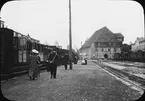 Skioptikonbild med motiv av resenärar vid tåg på tågstation.
Bilden har förvarats i kartong märkt: Höstresan 1910. Landskap 2. Granada 7. No 6. Text på bild: 