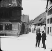 Skioptikonbild med motiv av två språkande män på gata, Klingen Strasse, i Rothenburg.
Bilden har förvarats i kartong märkt: Vårresan 1910. Rothenburg. XXX. Text på bild: 