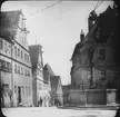 Skioptikonbild med motiv av skulpturen Seelbrunnen på torg i Rothenburg ob der Tauber.
Bilden har förvarats i kartong märkt: Vårresan 1910. Rothenburg. XXX.. Text på bild: 