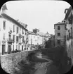 Skioptikonbild med motiv av gata vid floden Darro i Granada.
Bilden har förvarats i kartong märkt: Höstresan 1910. Granada 9. N:24. Text på bild: 