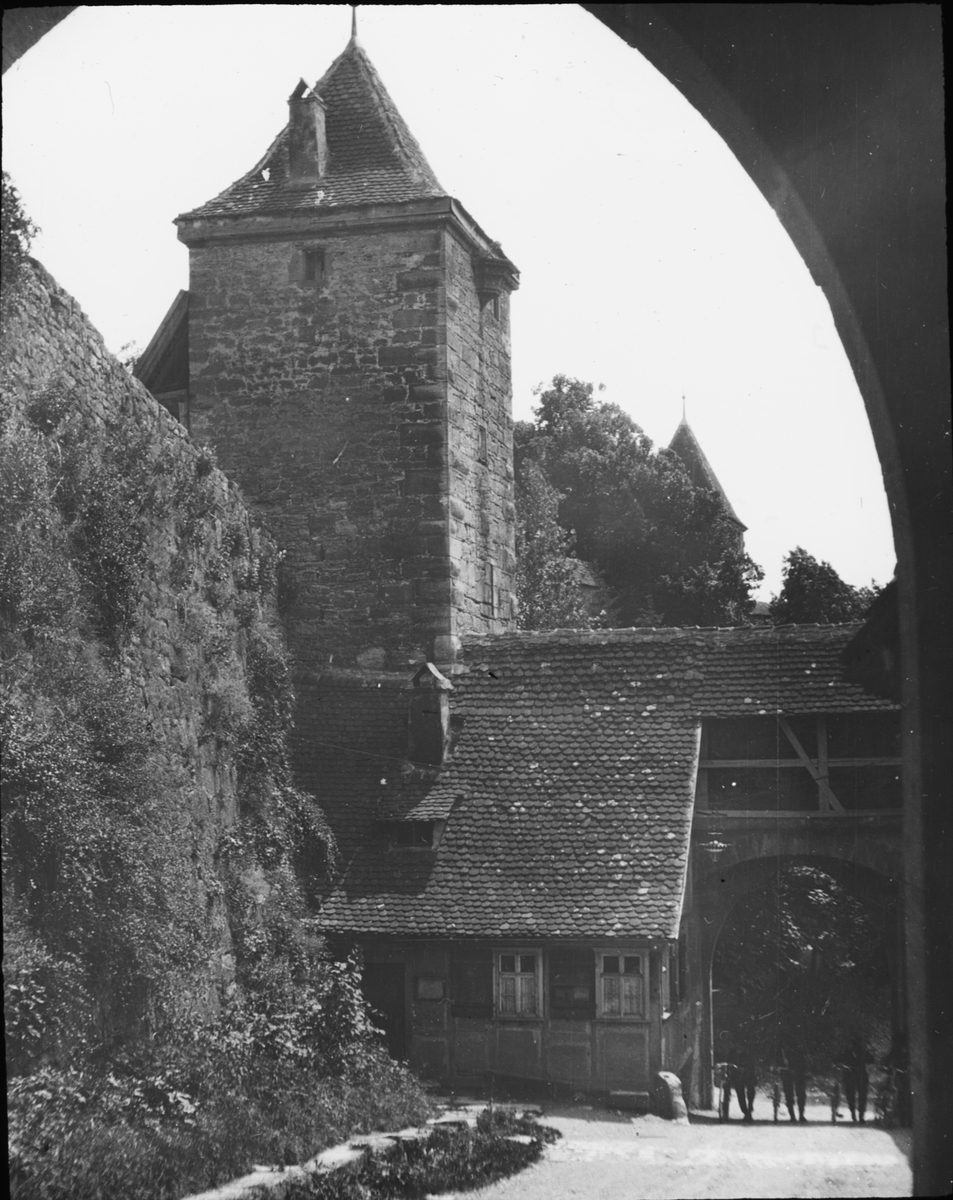 Skioptikonbild med motiv av Kobolzeller Tor i stadsmuren, Rotenburg ob der Tauber.
Bilden har förvarats i kartong märkt: Resan 1912. Rostock. Text på bild: "Fescherstrasse".