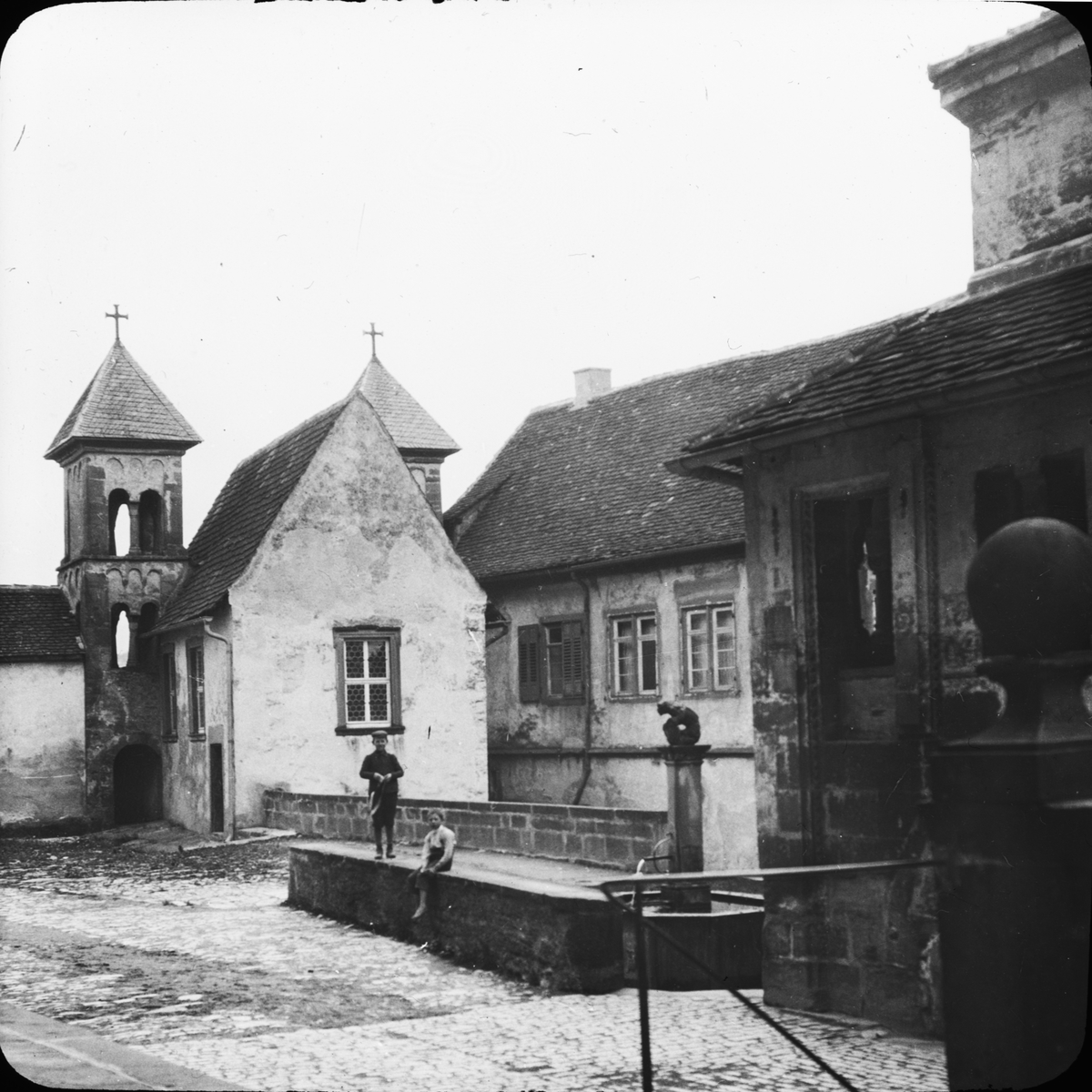 Skioptikonbild med motiv av två barn på gården vid Schloss Kronburg.
Bilden har förvarats i kartong märkt: Resan 1911 Schwäbische Hall. Schloss Kronburg. XIX. Text på bild: "Schwäbische Hall. Schloss Kronburg".