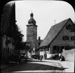 Skioptikonbild med motiv från Dinkelsbühl med stadsporten Segringer Tor i bakgrunden.
Bilden har förvarats i kartong märkt: Resan 1911. Dinkelsbühl 10.V. Text på bild: 