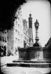 Skioptikonbild med motiv av fontänen Herrnbrunnen i Rothenburg, med tornet till St. Jakobs Kirche i bakgrunden.
Bilden har förvarats i kartong märkt: Vårresan 1910. Rothenburg. XXV.