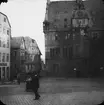 Skioptikonbild med motiv av man framför rådhuset i Marburg.
Bilden har förvarats i kartong märkt: Resan 1904. Marburg.