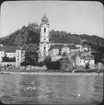 Skioptikonbild med motiv från Durnstein vid stranden av Donau i Österrike.På bilen syns den blå kyrkan, Die blaue Kirche.
Bilden har förvarats i kartong märkt: Höstresan 1909. Donau 8. No:5.