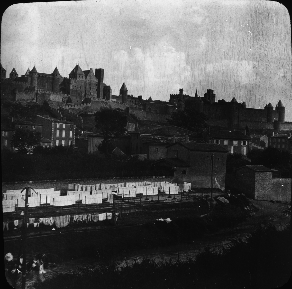 Skioptikonbild med motiv av vy över Carcassonne med medeltida borgen Cité de Carcassonne i bakgrunden.
Bilden har förvarats i kartong märkt: Höstresan 1907. Carcassonne 7. No:14.