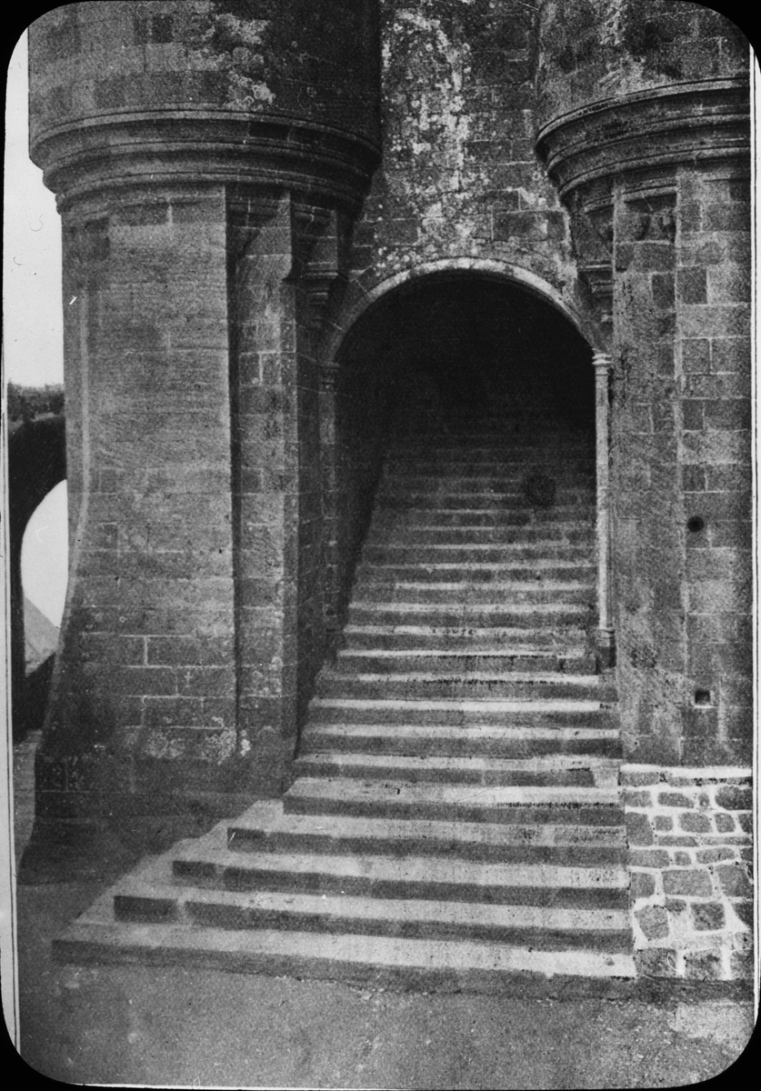 Skioptikonbild med motiv fån Châlet Le Mont Saint Michel.
Bilden har förvarats i kartong märkt: Resan 1908. St. Michel 8. XIII. Text på bild: "Le Chatelet (Entrèe de Labbaye)".