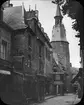 Skioptikonbild med motiv av tornet Tour de l'Horloge i Dinan, sett från Rue de l'Horloge.

Bilden har förvarats i kartong märkt: Resan 1908. Dinan 7. XV