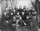 Gruppbild av den fulltaliga personalen vid Liljeholmens Stubinfabrik 1892, föregångaren till ASEA Kabel i Västberga. Fotot togs som födelsedagspresent till den 27-årige verkmästaren August Jansson.Hans far, John Jansson, hade lett fabriken från dess grundande 1870. Den låg vid Trekanten på Tunnelbanestationens plats.Redan i slutet av 1870-talet inleddes  tillverkning av tågvirke vid sidan av stubinfabrikationen.På 80-talet startades den avdelning för elektrisk ledningsmateriel som skulle leva vidare. Vid starten hade John Jansson två medhjälpare: Oskar Falk (mannen nr 2 från höger i andra sittande raden) och verkmästare August Janssons faster Charlotte (kvinnan nr 2 från höger i andra raden).