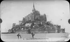 Skioptikonbild med tryckt motiv av Mont-Saint-Michel.
Bilden har förvarats i kartong märkt: Resan 1904. St. Michel. XII.