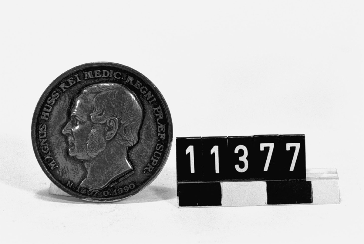 Medalj i silver över Magnus Huss, född 1807, död 1890. Tjocklek 3 mm. Slagen av Vetenskapsakademien år 1892. Åtsidan: Porträtt i lågrelief av Magnus Huss, vänster profil med text runtom: "MAGNUS HUSS REI MEDIC. REGNI PRAEF. SUPR. N. 1807 O. 1890". Frånsidan: En örn som lyfter vingarna mot solen ifrån en aeskulapiistav i lågor. Text: "IMMORTALITATIS NON FALLIT SPES. SOCIO MEDICO MERITISSIMO REG. ACAD. SUEC. MDCCCXCII". Signerad: Lea Ahlborn