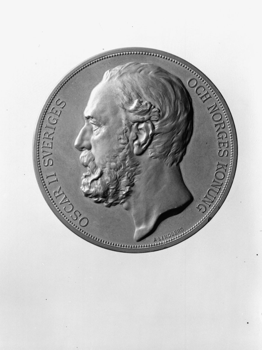 I brons slagen till minne av Sextonde Allm. Sv. Lantbruksmötet 1886. Tjocklek 5 mm. Tillägnad G. de Laval. I etui. Åtsidan: Vänster profil av Oscar II med text runtom: "OSCAR II SVERIGES OCH NORGES KONUNG". Frånsidan: Kvinnofigur och diverse emblem samt text: "SEXTONDE ALLM. SVENSKA LANDTBRUKSMÖTET 1886. G. DE LAVAL ERINRAN". Signerad: A. Lindberg.