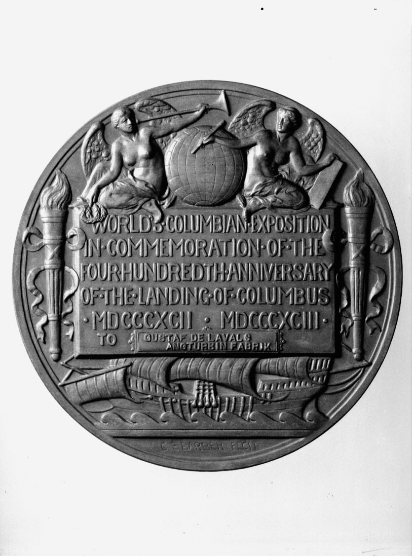 Medalj, gjuten i brons, till minne av Columbus landstigning. Har tillhört Gustaf de Laval. Tjocklek 60 mm. Från världsutställningen i Chicago 1892. I etui. Åtsidan: Bild av Columbus med flagga i bakgrunden och "CHRISTOPHER COLUMBUS OCT. XII MCCCCXCII". Frånsidan: Jordglob med kvinnofigurer, facklor samt skepp. Text: "WORLD'S COLUMBIAN EXPOSITION# IN COMMEMORATION OF THE, FOUR HUNDREDT ANNIVERSARY, OF THE LANDING IN COLUMBUS, MDCCCXCII. MDCCCXCIII, TO GUSTAF DE LAVALS ANGTURBIN FABRIK". Signerad: C.E. Barber Tecit.