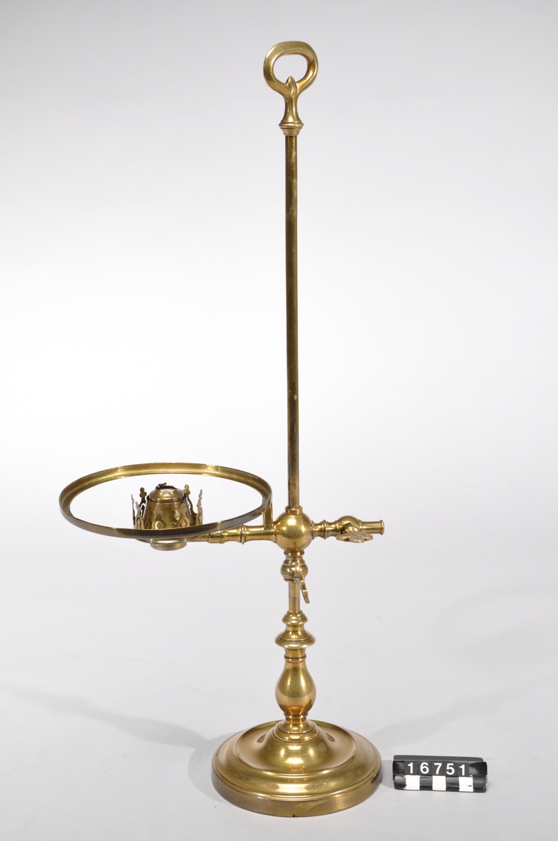 Bordslampa med höj- och sänkbar brännare av porslin samt lampkupa och kupring. Lampkupa: TM 18.136. En flisa borta ur kupans nedre hals. Lampglas saknas dock.
Tillbehör: Lösa delar: lampfot, kupring, lampkupa.