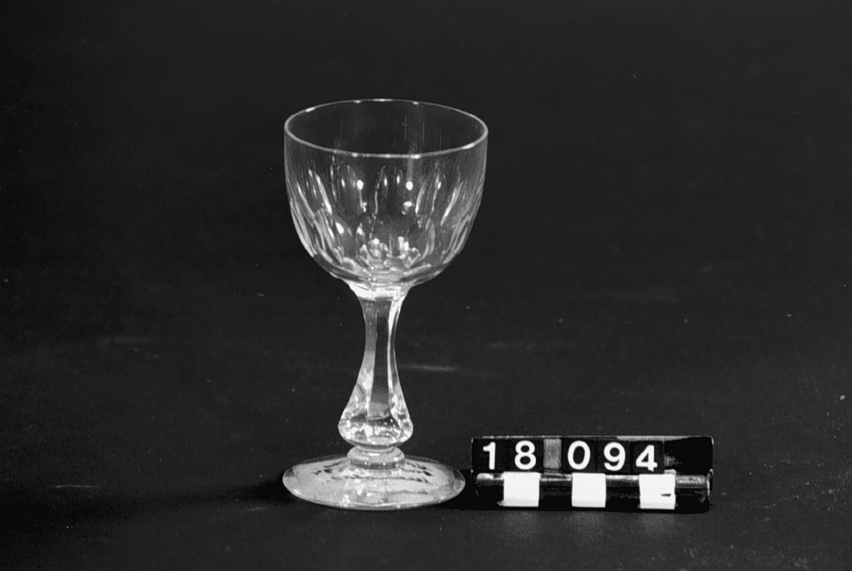 Vinglas (Rhenvinsglas) med ljusgrön kupa av "uranglas" och fot av ofärgat glas. Etikett: "Kosta glasbruk 1894. Uranglas".