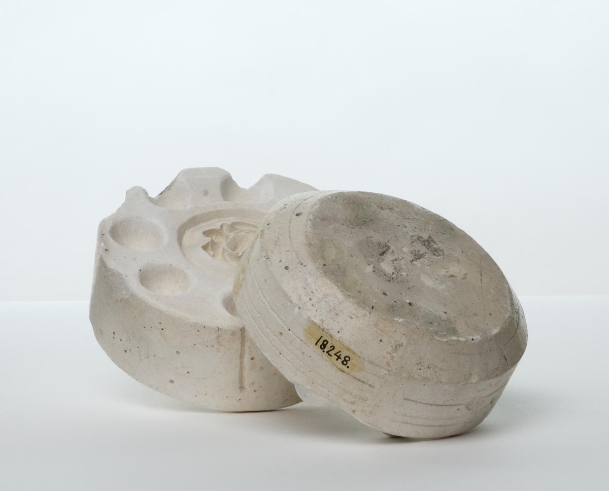 Kanna, ur en serie prov visande tillverkning av en kaffekanna av flintgods. Från gjutning i gipsform till färdig vara, med dekor tryckt under glasyren. 
f) Lösa delar förknippade med tillverkning av kannan:
    -gipsform i fyra halvor för kannan. Höjd: 265 mm, diameter: 200 mm, vikt: 7,8 kg. 
    -gipsform i två halvor för lock. Höjd: 90 mm, diameter: 160 mm, vikt: 1,8 kg. 
    -gipsform i två halvor för henkel. Höjd: 80 mm, diameter: 115 mm, vikt: 0,9 kg. 
    -gipsform i två halvor för pipen. Längd: 200 mm, bredd: 110 mm, höjd: 120 mm, vikt: 2,3 kg. 
    -gipsform i två halvor för bottenplatta. Höjd: 100 mm, diameter: 170 mm, vikt: 1,9 kg., 
    -form i två halvor för locket. Höjd: 90 mm, diameter: 145 mm, vikt: 1,8 kg.