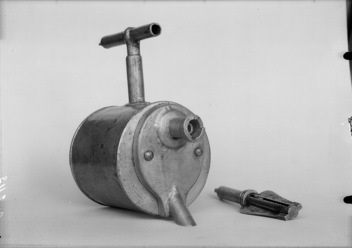 Christopher Polhem's strange tap, made of tinplate with the fixed parts riveted and soldered. The gear and its sleeve, the sleeve on the pipe and a liner in the drain of the container are made of brass. The tap is to be mounted in the barrel. The amount of liquid that is drawn out is portioned with a key. It also functioned as a lock and limited access to the barrel's contents. This specimen was probably exhibited at the 1866 exhibition in Stockholm, by "Stiernsunds Bruksegare", according to a contemporary exhibition catalogue.