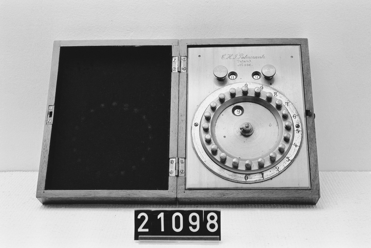 Räknemaskin för addition och multiplikation. "C.H.J. Palmcrantz Patent Nr 106". Monterad i ram av mässing med botten, tre skruvar saknas, i låda av mahogny. Etuiet: 185 x 140 x 50.