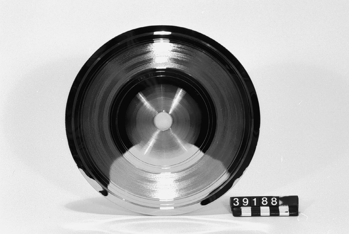 Pressmatris vid tillverkning av grammofonskivor. Galvaniskt framställd nickelplåt. Höjd: 0,3 mm. Centrumhål diameter: 20 mm.