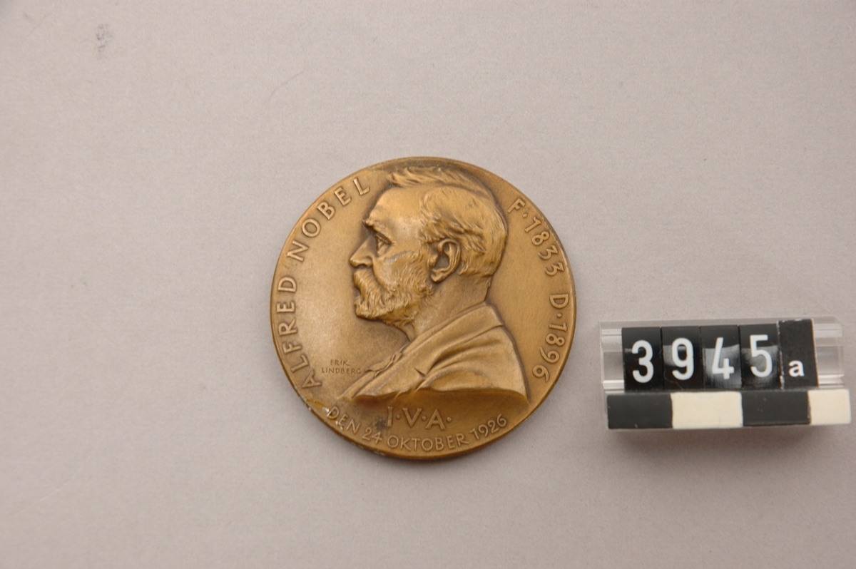 Medalj av brons i etui, slagen av Ingenjörsvetenskapsakademien över Alfred Nobel. Tjocklek: 25 mm. Åtsidan: bröstbild i lågrelief och text: "Alfred Nobel f. 1833, d. 1896. I.V.A. den 24 oktober 1926". Frånsidan: "Prometeusfigur i lågrelief. Graverad av Erik Lindberg.