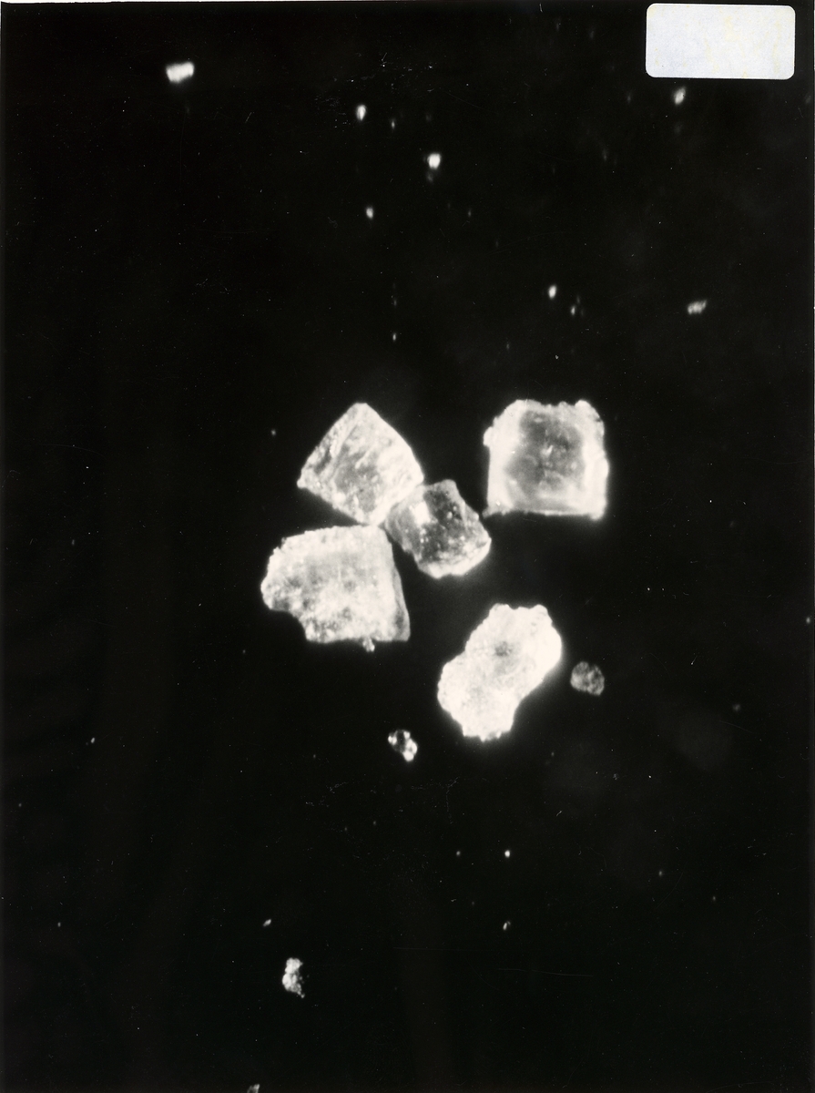 Diverse syntetiska diamanter. - Nicodur: metallbelagda diamanter. - RBD: diamanter för plastbundna slipskivor. - 140/170 RS: tidiga syntetiska diamanter ca 1963-1965 - Inplastat snitt av centralkapsel till Q-20. Diamanter framställda i högtryckskammare (P=5000 atm., T=1600 gr C., Diamanterna syns mellan koboltskivorna. - Hårdmetallstans till Hp-apparat Q-12. - Co-skivor till Q-20. - Diamanter för metallbundna slipskivor.