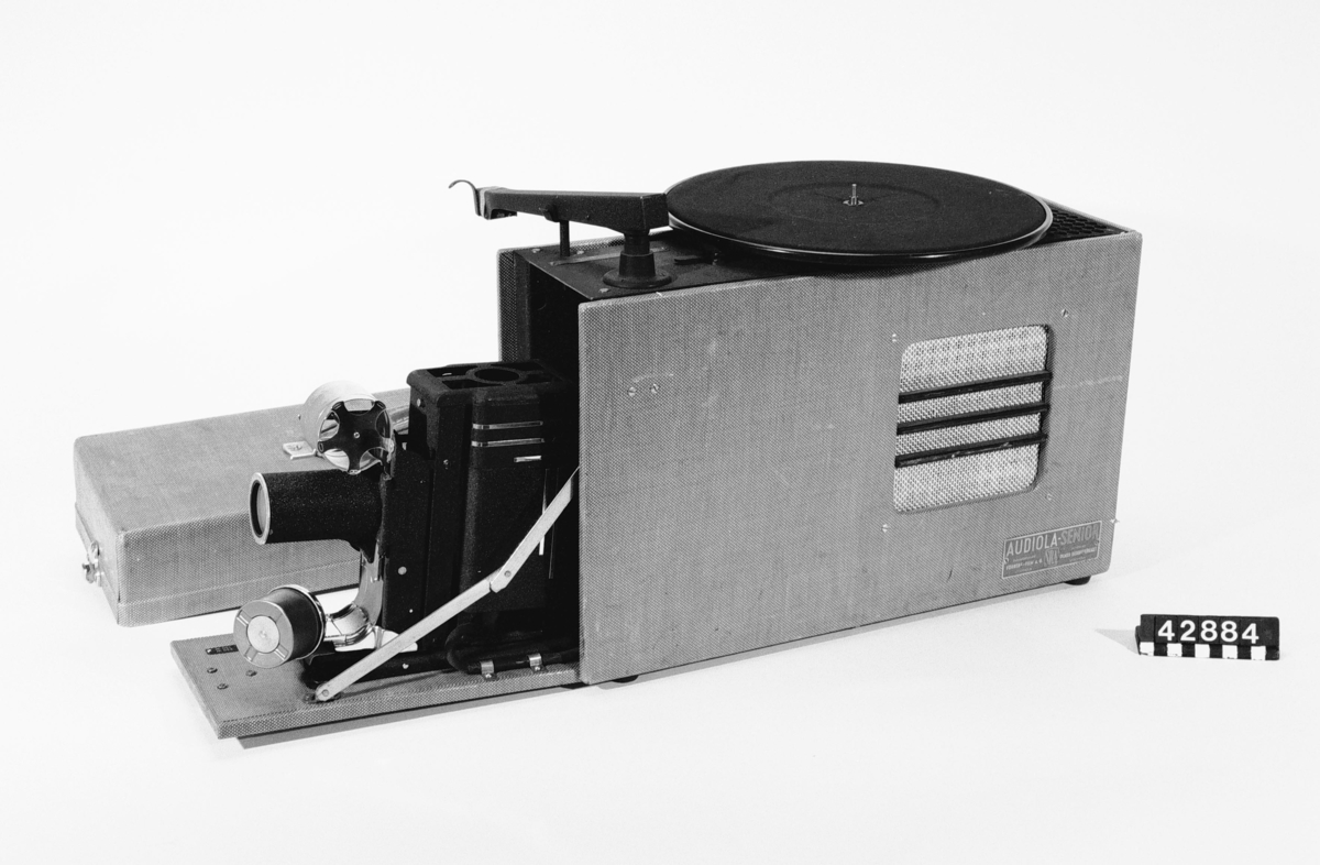 Grammofon och projektor för bildband, skolmodell. Ryms i en väska men kan i utfällt läge visa ett bildband och spela upp komentarer och musik. Skivtallriken är avtagbar.