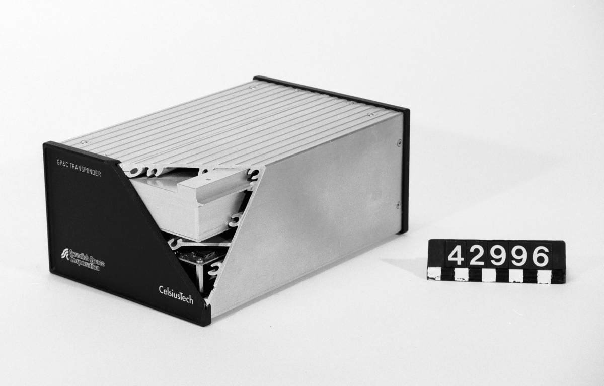 Denna apparatlåda är en prototyp från 1994 till den av Håkan Lans uppfunna datalänken. En satellitnavigator, GPS och en datorstyrd VHF-radio utgör centralenhet, ofta kallad för transponder. Apparatlådan visas uppskuren. Övre delen innehåller den speciella VHF-radion, som sänder och tar emot datameddelanden. Den nedre delen innehåller GPS-mottagare, datordel och kraftenhet. GP&C står för Global Positioning & Communication.  Transpondrarna ingår i system ombord på fartyg eller flygplan där de dels håller reda på position via GPS-systemet, dels kommunicerar via VHF-radio med andra transpondrar med uppgifter om den egna farkostens färdriktning, hastighet och position. Den insamlade information presenteras på bildskärmar så att den egna geografiska positionen syns tillsammans med andra farkoster i området. Informationen kan också samlas in av flygledning eller kustbevakning för att följa och övervaka trafik.