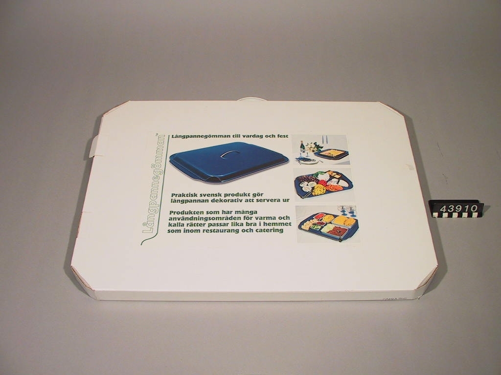 Bricka med lock. På brickan kan en hel ugnsplåt, långpanna, rymmas och serveringen direkt från långpannan kan därmed göras mer tilltalande. Locket används för att hålla maten varm, eller kall. Tillverkad av 3 mm formpressad furufanér, belagd med ett värmetåligt ytskikt av melamin.