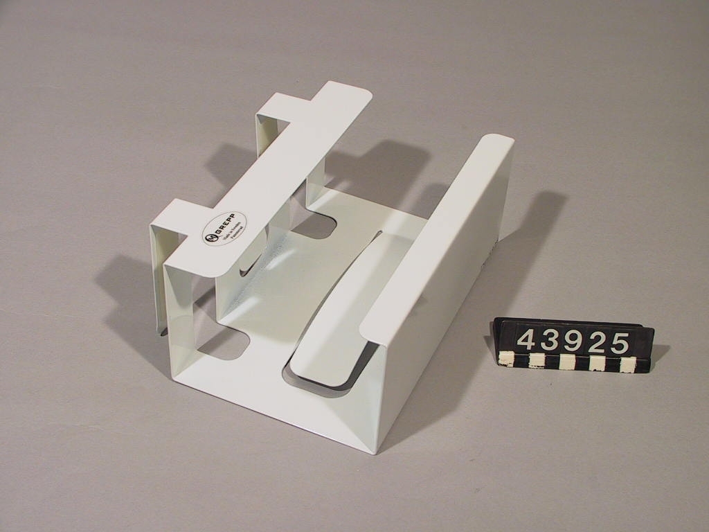 Hållare för förpackningar med engångshandskar. Hållaren passar de flesta typer av engångshandskar i 100-pack som används inom vård och omsorg, restaurang, storkök m.m. Hållaren kläms fast under en hylla