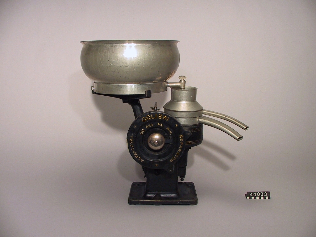 Separator från Alfa-Laval modell Colibri. Stora kärlet märkt Colibri III, 150 liter. På tappkranen finns "4465" ingjutet. Separatorn märkt 60 Rev.Pr.Min. Vev med trähandtag. 
Diameter: 100 mm, höjd: 410 mm. fyra träskruv inkl. träbrickor för fastsättning av maskinen. Plåtask märkt: "ALFA-LAVAL SEPARATOR" med div. smådelar. Smutsig och färgavskrapad.
Tillbehör: egentillverkad träpinne på fat för upphängning av maskindelar.