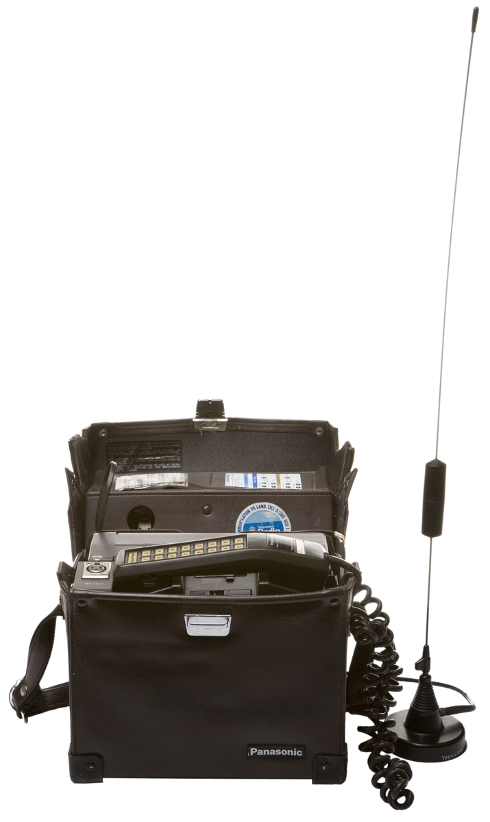 Bärbar NMT 450 mobiltelefon i läderväska, antenn med magnetfotfäste för användning i exempelvis bil.
Tillbehör: Separat antenn samt läderväska.