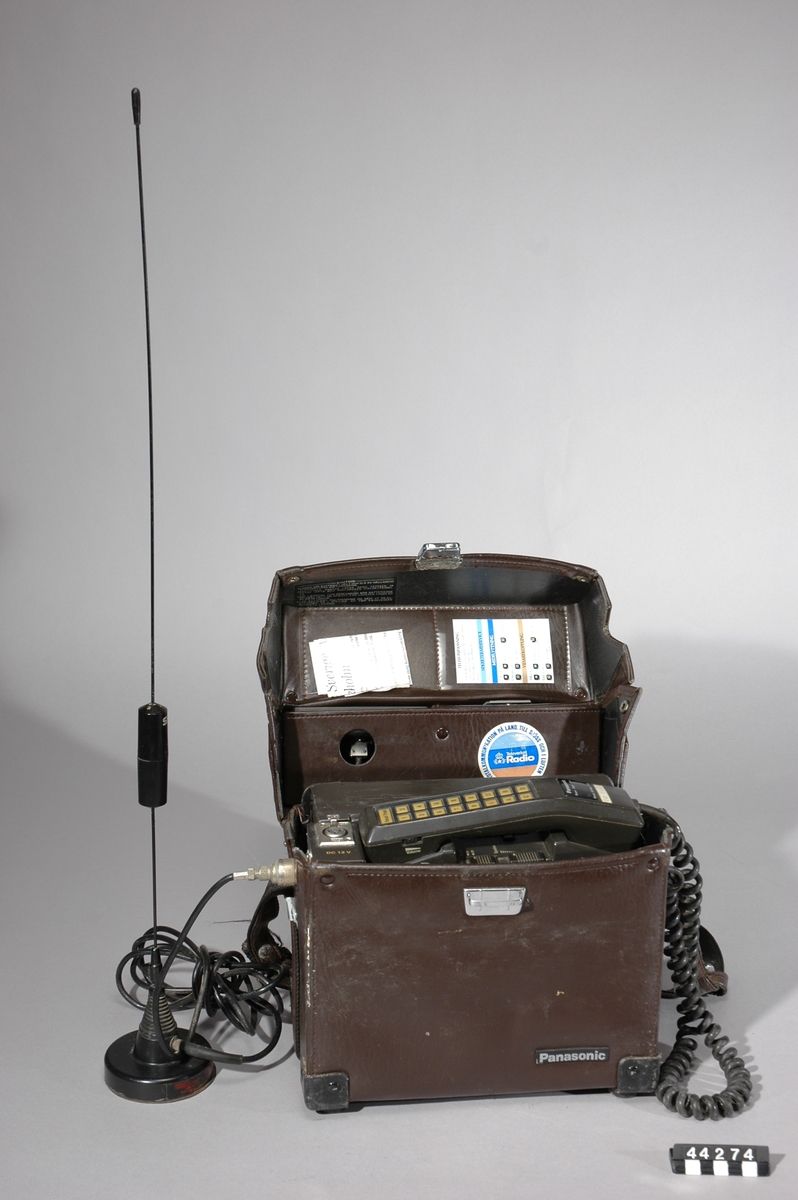 Bärbar NMT 450 mobiltelefon i läderväska, antenn med magnetfotfäste för användning i exempelvis bil.
Tillbehör: Separat antenn samt läderväska.