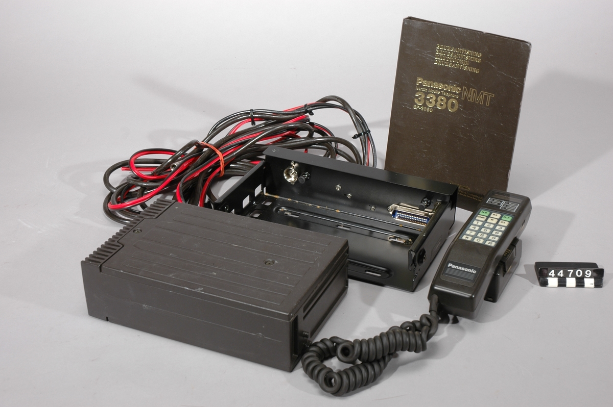 NMT 450 biltelefon i väska. Mobiltelefon med separat mottagardel och monteringsenhet. Mottagaren: model EF 3380 XQ, serienr XB 26397, mått: L-153mm,B-250mm,H-72mm,vikt-2,95kg,brun. Monteringsenheten: model EZ-450, serienr AX-29931, mått: L-170mm,B-260mm,H-65mm,vikt-1,8kg,svart. Telefonlur: model EFM 1135,serienr 1024,mått: L-205mm,B-53mm,H50mm, Telefonlurshållare: model EFJ 1064,serienr 1224, mått: L-103mm,B-63mm,H-48mm,vikt lur och hållare tillsammans-0,55kg.