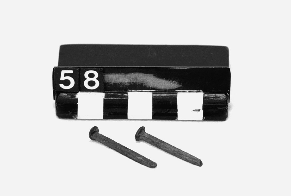 Framställda genom varmsmidning i maskin, s.k. präss-spik. Spikarna visa gränsen uppåt och nedåt (största och minsta spik) för denna tillverkning i Sverige. Mått, den större spiken: längd: 280 mm, diamanter: 28mm. Den mindre: längd: 32 mm, diameter: 6mm. Text på etikett: "Största och minsta präss-spik från Skyllberg. Present af Carl Sahlin 1922".