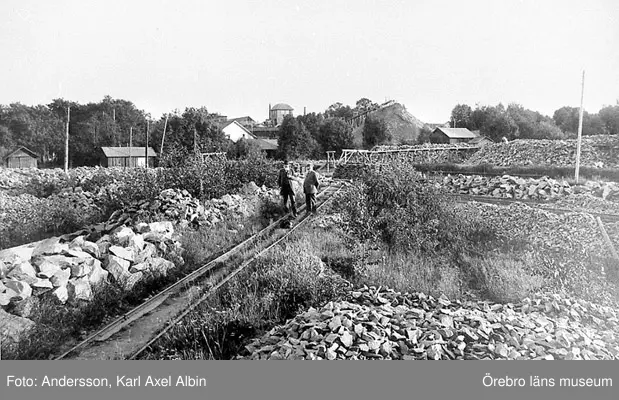 Hytt- och gruvbyn Pershyttan. Bilden är tagen vid Lockgruvans ruschbanas ändpunkt där också det bredspåriga stickspåret från år 1873 har sin ändpunkt. På bilden står hembygdsforskaren Johan Johansson (tv) och gruvförvaltaren Frans Larsson (th).