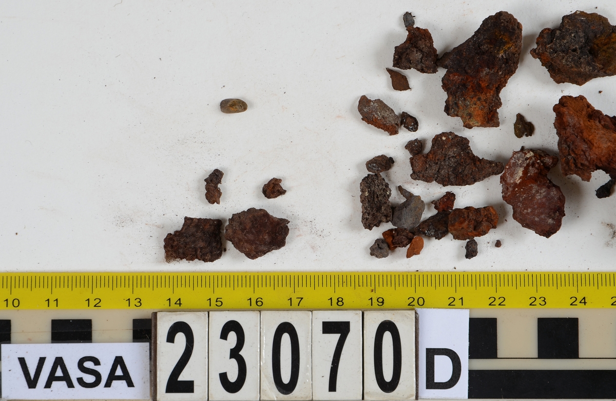 Sko.
Inuti skorna hittades även fragment från olika textilier som ursprungligen varit ett par strumpor. Idag sitter ett stickat fragment av ull fast i vänsterskon (23070) med avigsidan uppåt. I fyndet finns även en mängd lösa stickade fragment som idag är mycket korroderade och vissa helt mineraliserade av järn vilket har gjort textilen stenhård och därmed oerhört skör (23070a-c). Utifrån minskningar som några små fragment har så har det varit möjligt att rekonstruera strumpans tå. Genom att pussla ihop fragmenten som ursprungligen har suttit ihop har det på så vis gått att avgöra hur strumpans tå har varit konstruerad. Då textilen är så fragmentarisk är det inte möjligt att avgöra hur resten av strumpan har sett ut eller varit konstruerad. Däremot så finns det fragment av ett kypertvävt tyg av ull som på vissa ställen ligger dubbelt med det stickade 23070c). Ett av dessa fragment har stelnat i formen så som den suttit på fotens främre del inuti skon. Detta fragment täcker delvis det stickade tyget och har dessutom spår av kaststygn längs en kant. Så som det vävda tyget är placerat på det stickade tyget pekar på att man använt det som lagningslappar till sina stickade strumpor. 
I fyndet finns det även korroderade järnklumpar, ett tuskaftsvävt tyg av ull och rester av ett grovt bastfibergarn och två mindre läderfragment (23070d-f). Det är möjligt att även dessa har tillhört strumpan och/eller skon.

För mer detaljerad information från textildokumentationen (år 2022) se länkade filer.

Skodokumentation 2022:
Ovanläder. Tillverkad i getskinn av god kvalitet. Hör ihop med fyndnummer 23069 (Yngves skor). Tillverkades på en rak läst och bars på vänster fot. Inga dekorationer Det finns stygnhål som visar att det funnits invändiga förstärkningar (men förstärkningslappen saknas). Det finns delaminering men inga lagningar.
För mer information, se Länkade filer: Uppritning

Text in english:
This is the upper of a shoe of more “extreme fashion”, made of goatskin leather of good quality, probably made on a straight last and worn of the left foot, with no decorative features. The upper couples with 23069, together composing Yngve’s shoes. There are internal reinforcements missing from the upper and delamination, there are no repairs.
For more information, go to Länkade filer: Uppritning