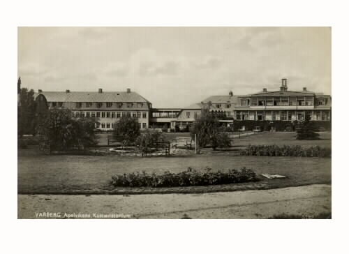 Vykort avsänt 1938, "Varberg, Apelvikens kustsanatorium." Vy från parken mot sanatoriebyggnaderna. I bildens mitt är en sittplats kring en liten rund damm arrangerad.