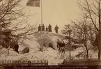 Fotografi af en 16fot hög snödrifva i Kockska trädgården den 21 mars 1888. Fotobild från den svåra snövintern i Skåne 1888. I grosshandlare Johan Kocks trädgård. Personer från vänster: 1. fröken Bertha Mörck, Trelleborg, 2. fröken Ida Reventberg, Trelleborg, 3. skolyngl. C. J. Reventberg, Trelleborg, 4. Handl. P. Nilsson, g. m. Bökman, Trelleborg, 5. Bokhållaren Hansson (till Kocks), Trelleborg, Fröken Karolina Borgström (Kia Petersen) sitter i förgrunden, framför de tre unge männen. Övr. nr. 89:0566, 13981.